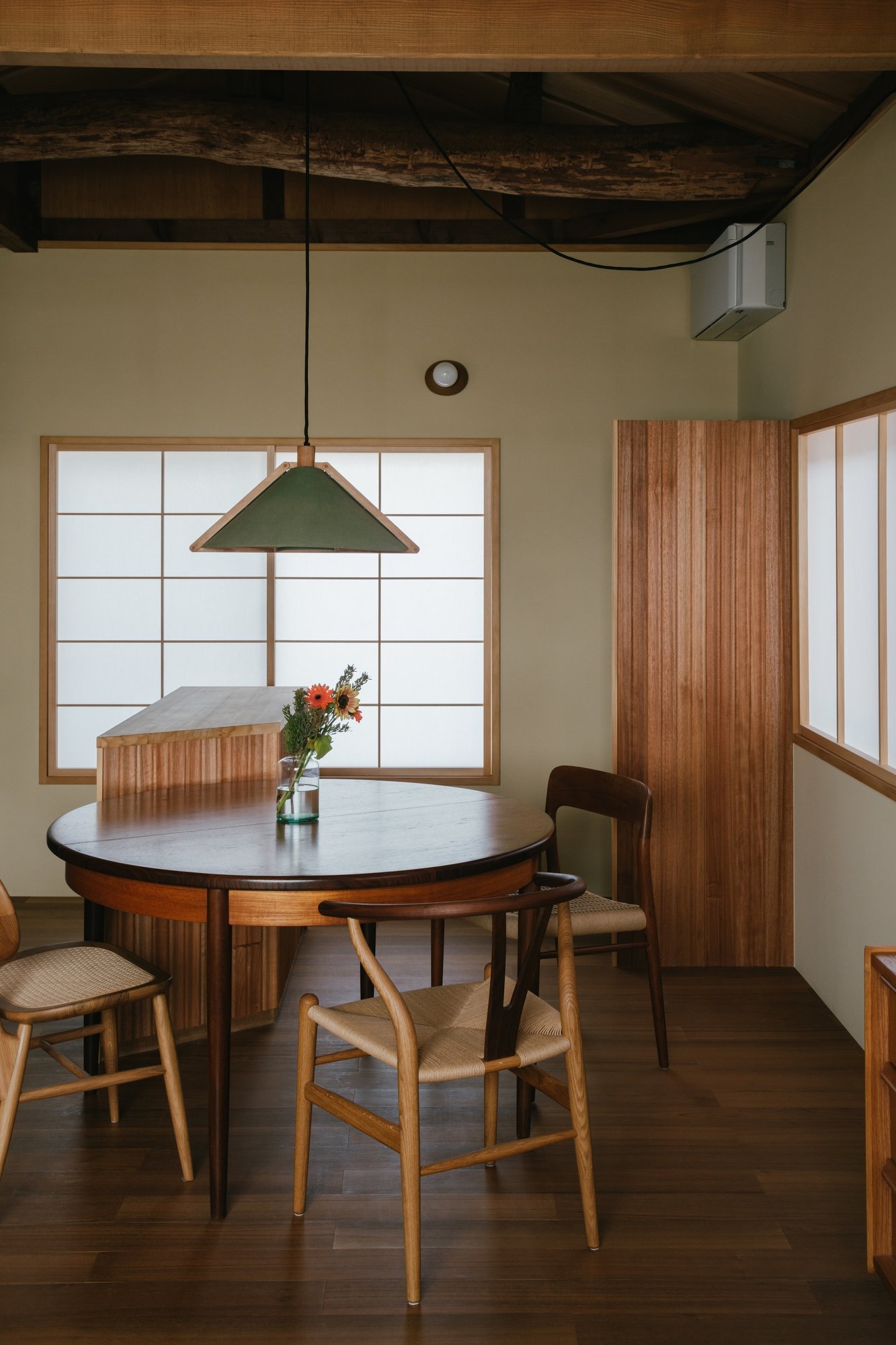 House in Akashi 목재 보 아래 원형 식탁과 삼각 펜던트 조명