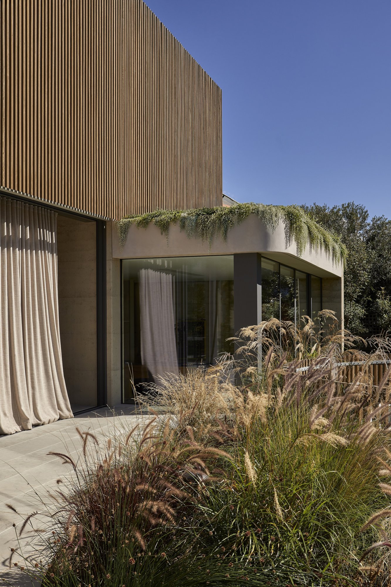 모서리를 유리로 연 Barwon Dunes House 외관과 해안 식재