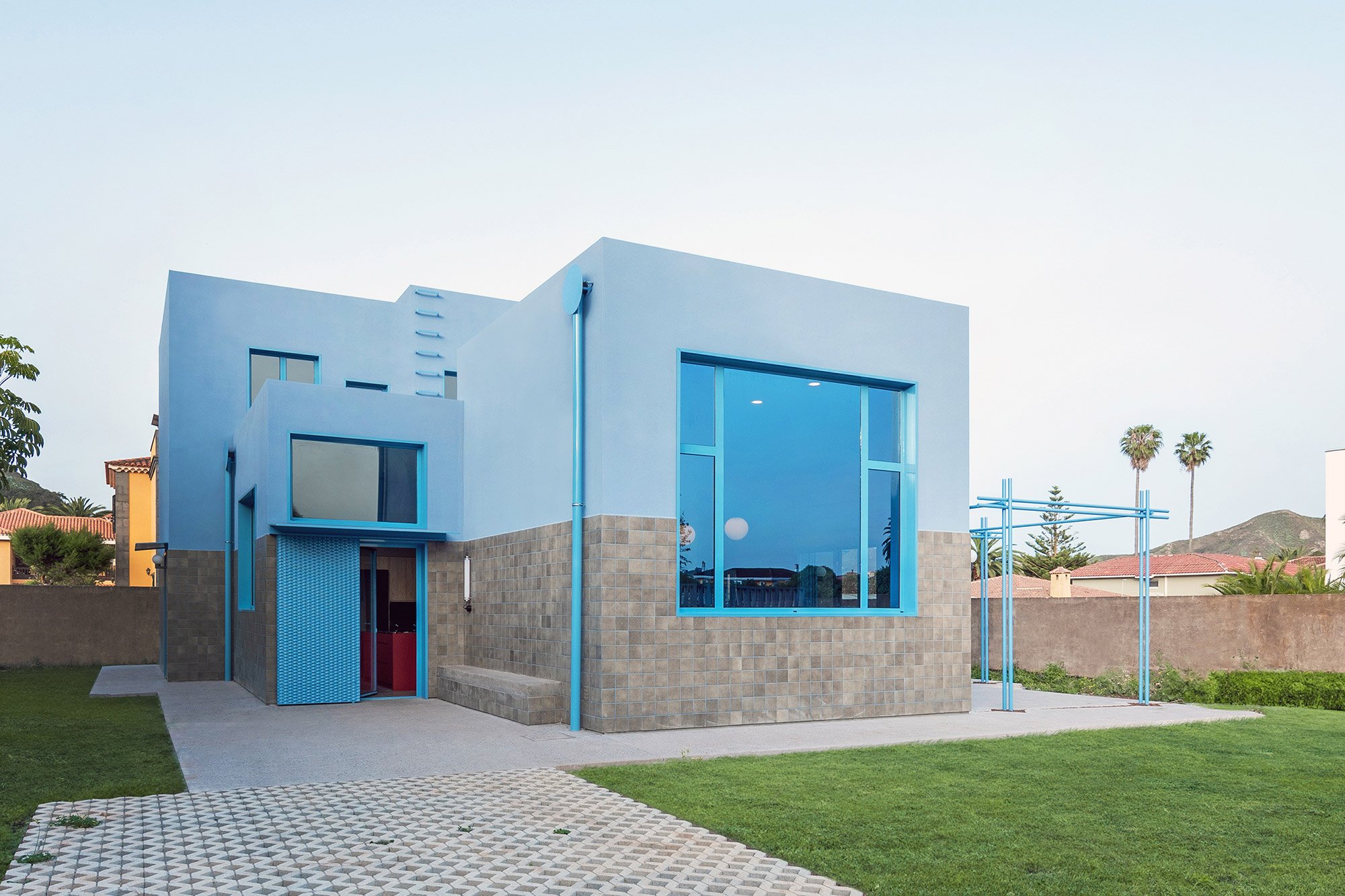 스카이블루 외벽과 정사각 타일 하단부가 대비되는 The Blue House 정면 외관