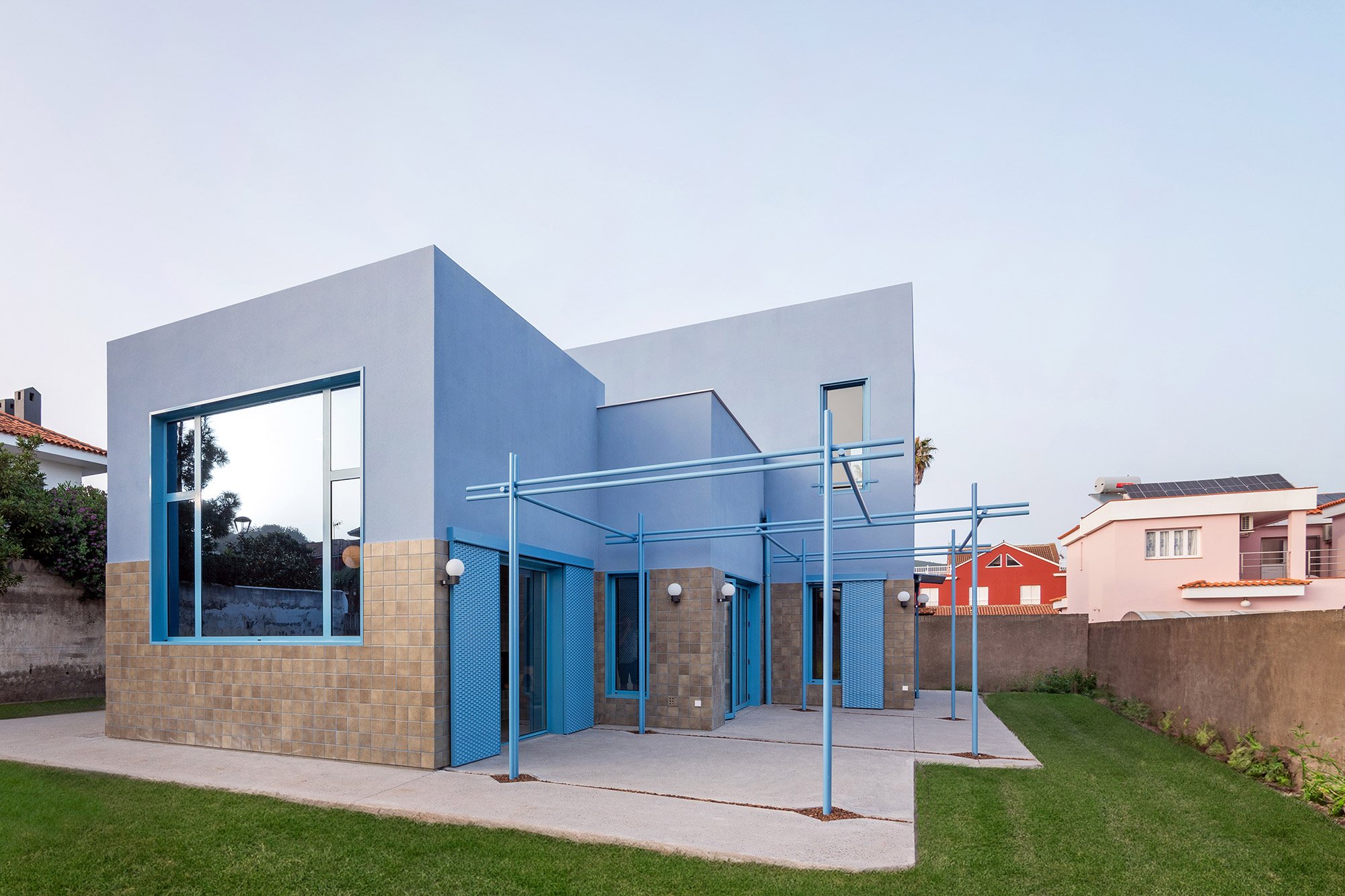 큐브 매스가 맞물린 The Blue House 측면 외관과 블루 철제 퍼걸러
