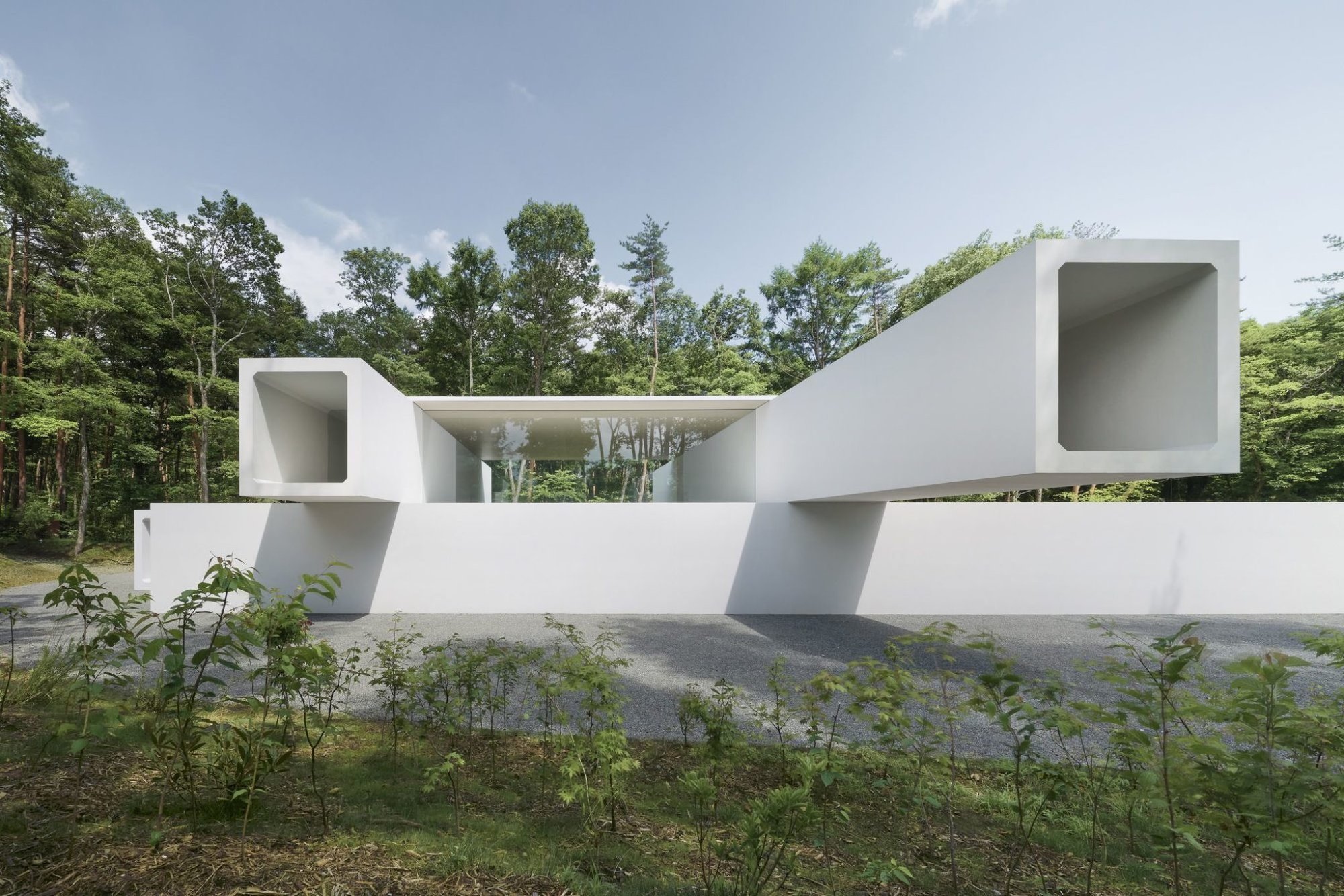 숲 앞으로 콘크리트 터널이 양쪽으로 뻗은 Culvert Guesthouse 입면