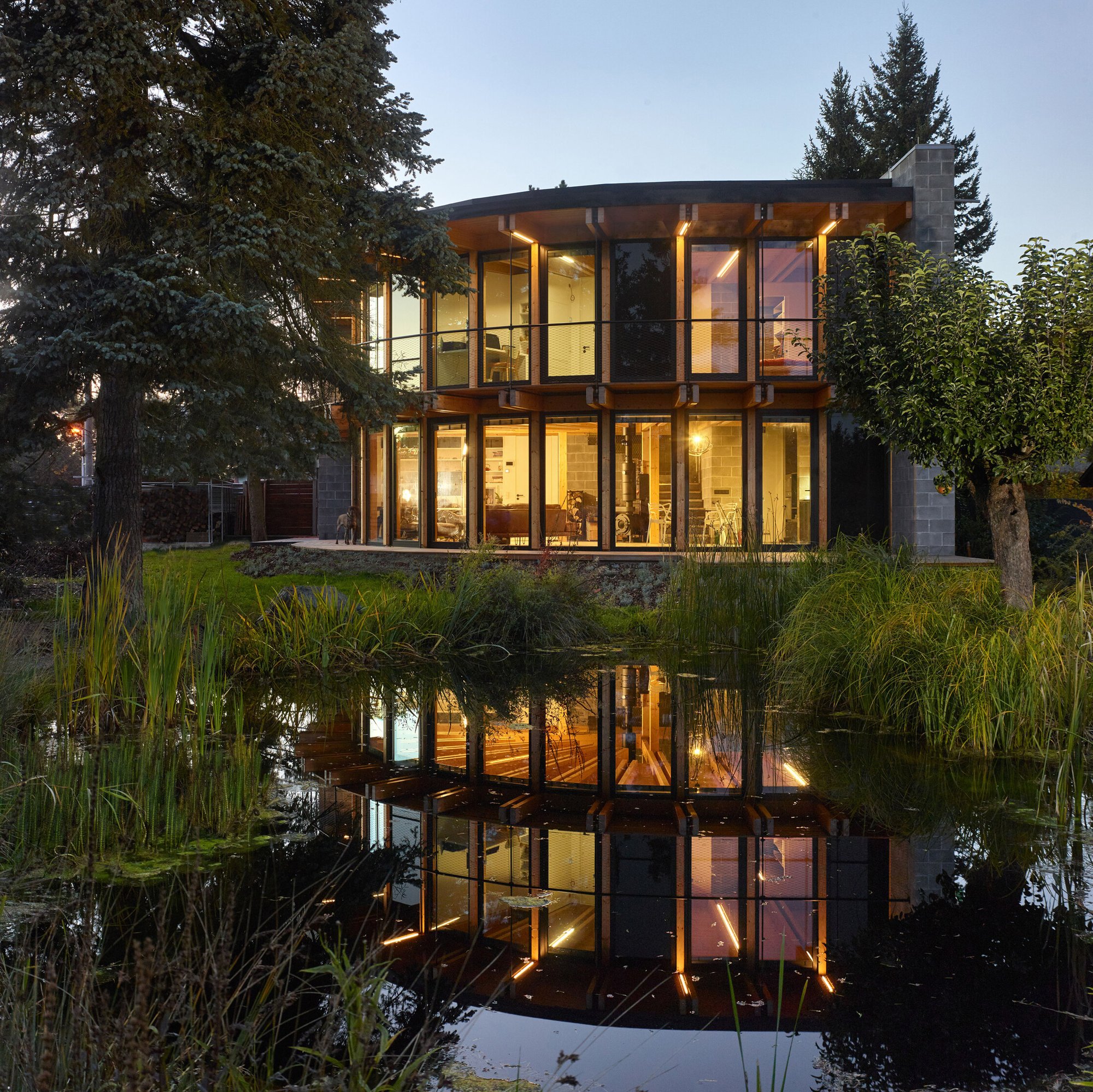 해 질 녘 연못에 비친 체코 목조주택 House That Opens Up to the Sun 곡면 유리 파사드