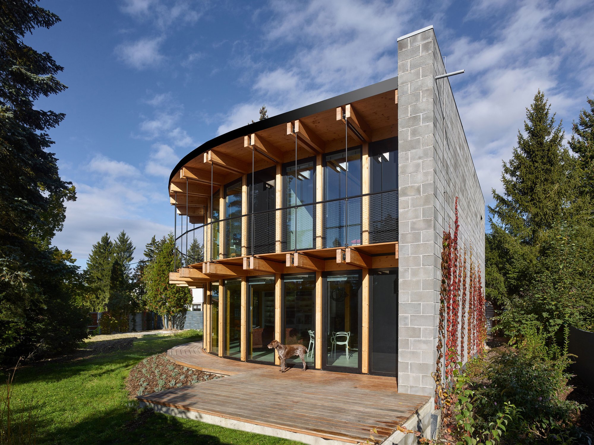 콘크리트 블록 벽 모서리와 목재 데크가 보이는 House That Opens Up to the Sun 측면 외관