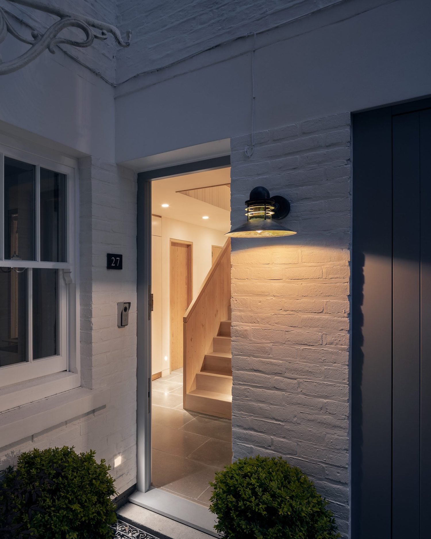 현관문 너머로 목재 계단이 보이는 Danish Mews House 출입구 야경