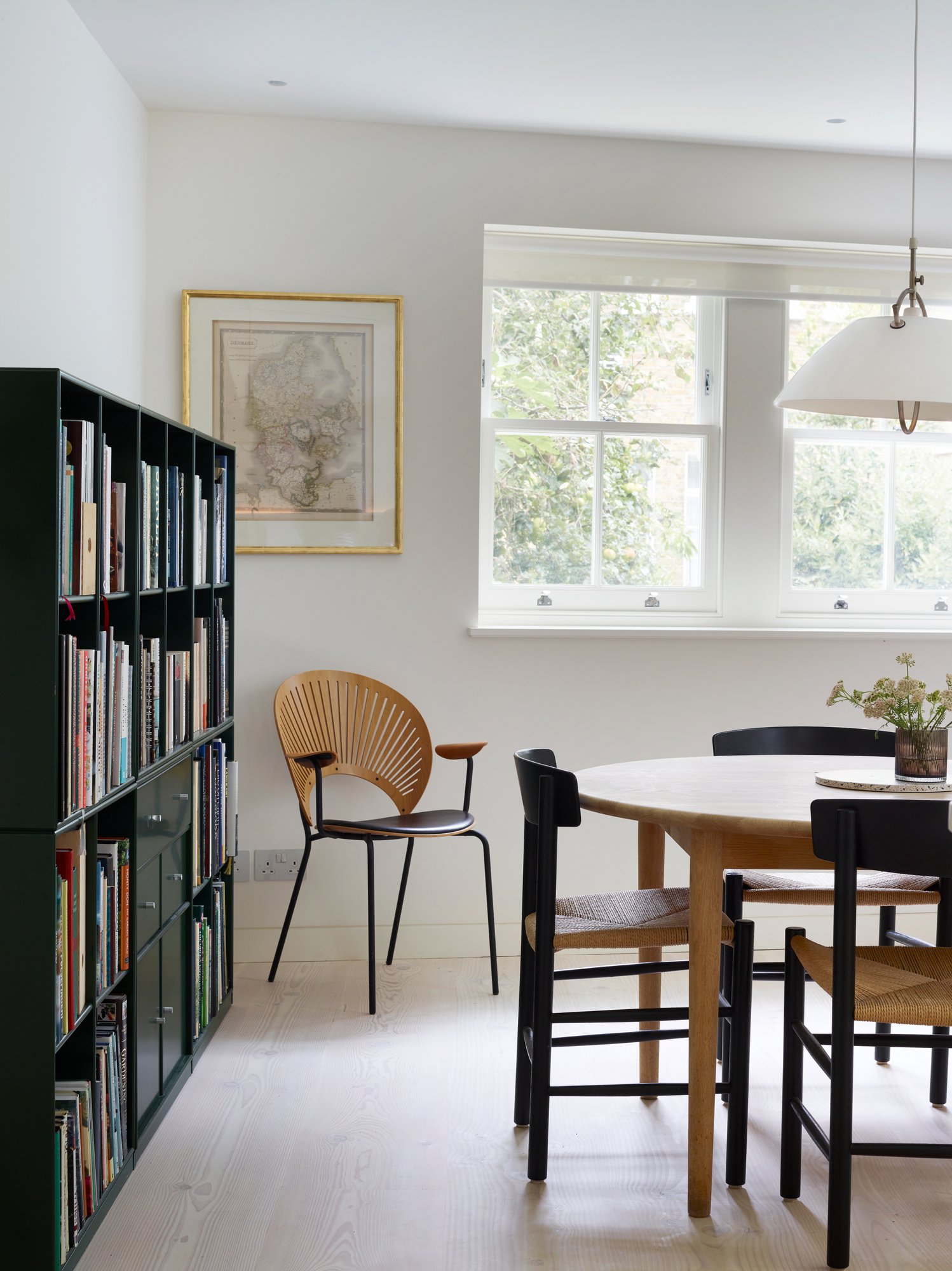 그린 책장과 원형 식탁이 놓인 Danish Mews House 창가 다이닝