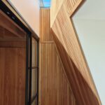 천창 빛이 목재 벽을 타고 내려오는 Danish Mews House 계단실
