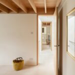 노출 목재 보 아래 라탄 바구니가 놓인 Danish Mews House 복도