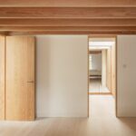 목재 보 아래 원목 문이 이어지는 Danish Mews House 실내