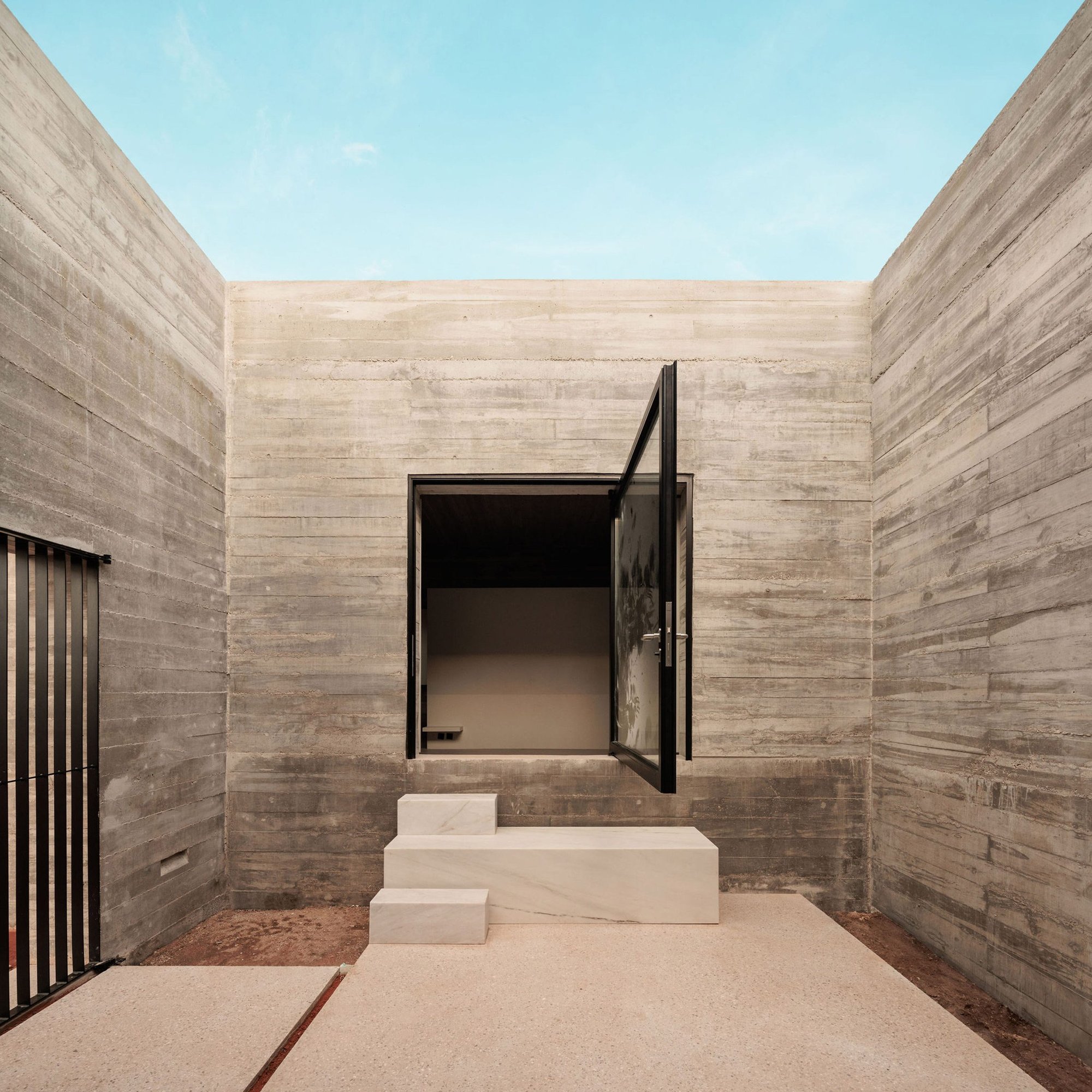 하늘로 열린 콘크리트 현관 중정과 피벗 도어