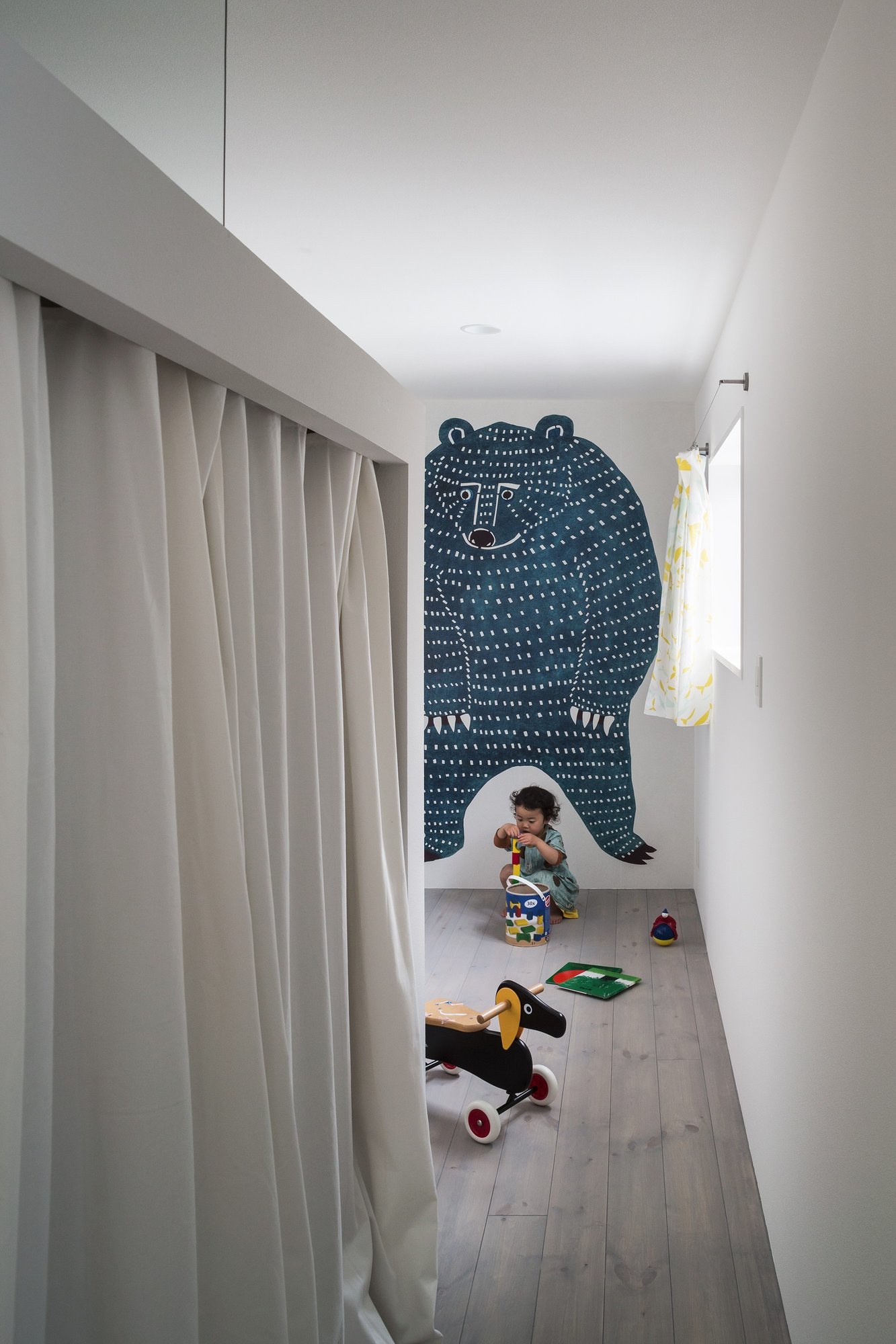 곰 그림 벽과 화이트 커튼으로 구획한 Framing House 아이방