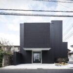 낮에 정면에서 본 Framing House 블랙 파사드와 진입 통로