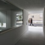 통로 양쪽 창 너머로 거리 행인이 지나가는 Framing House