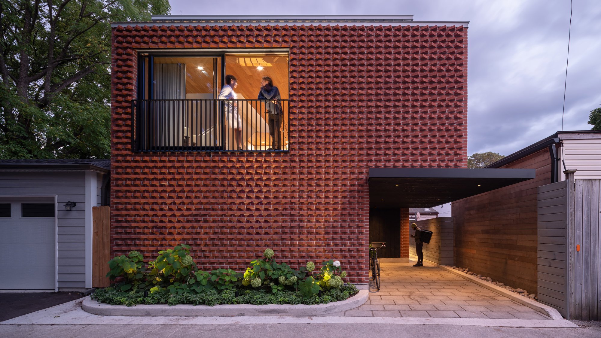 해 질 녘 골목에서 본 Garden Laneway House 벽돌 파사드와 카포트