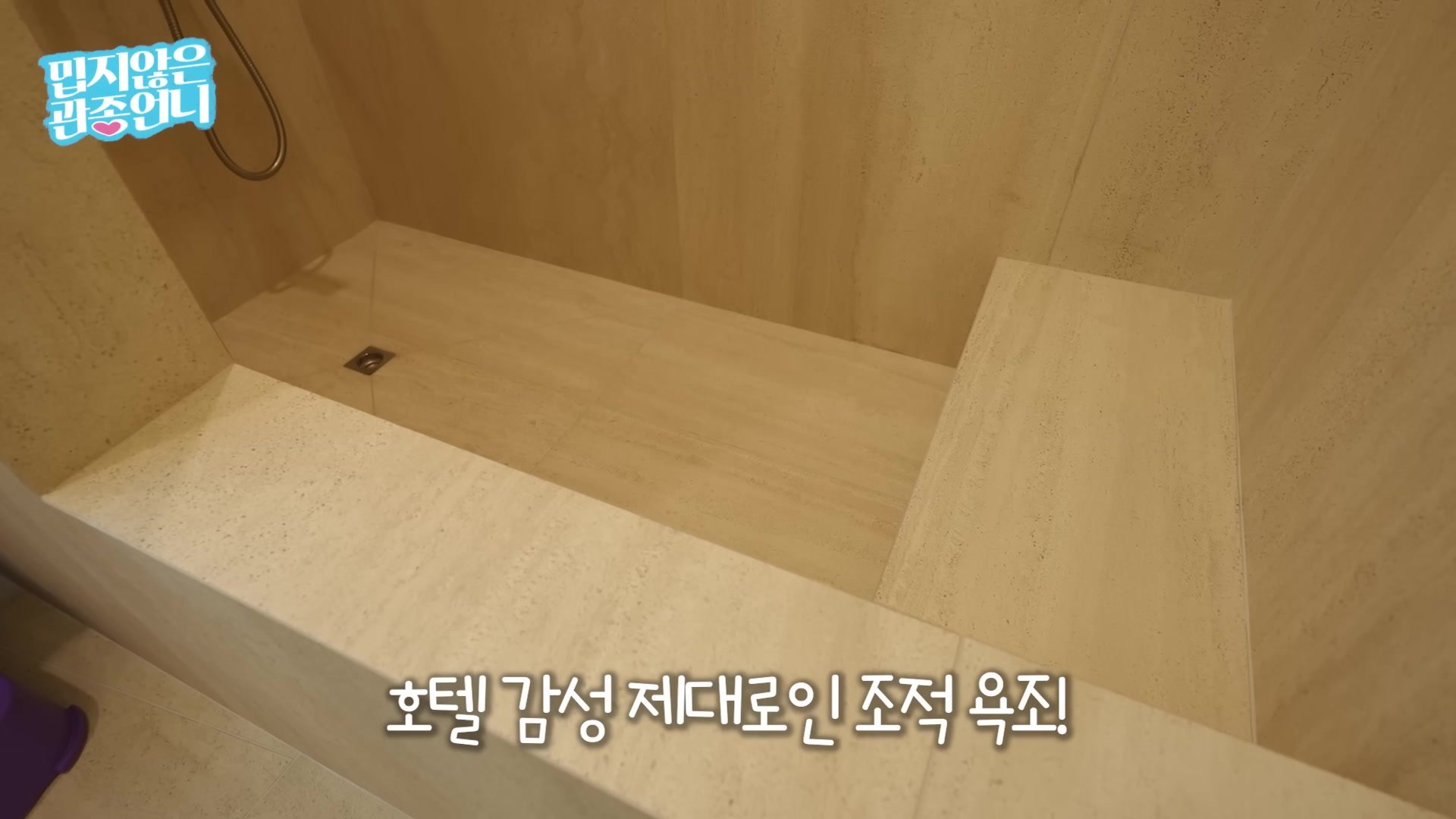 따뜻한 석재 톤 타일로 감싼 조적 욕조
