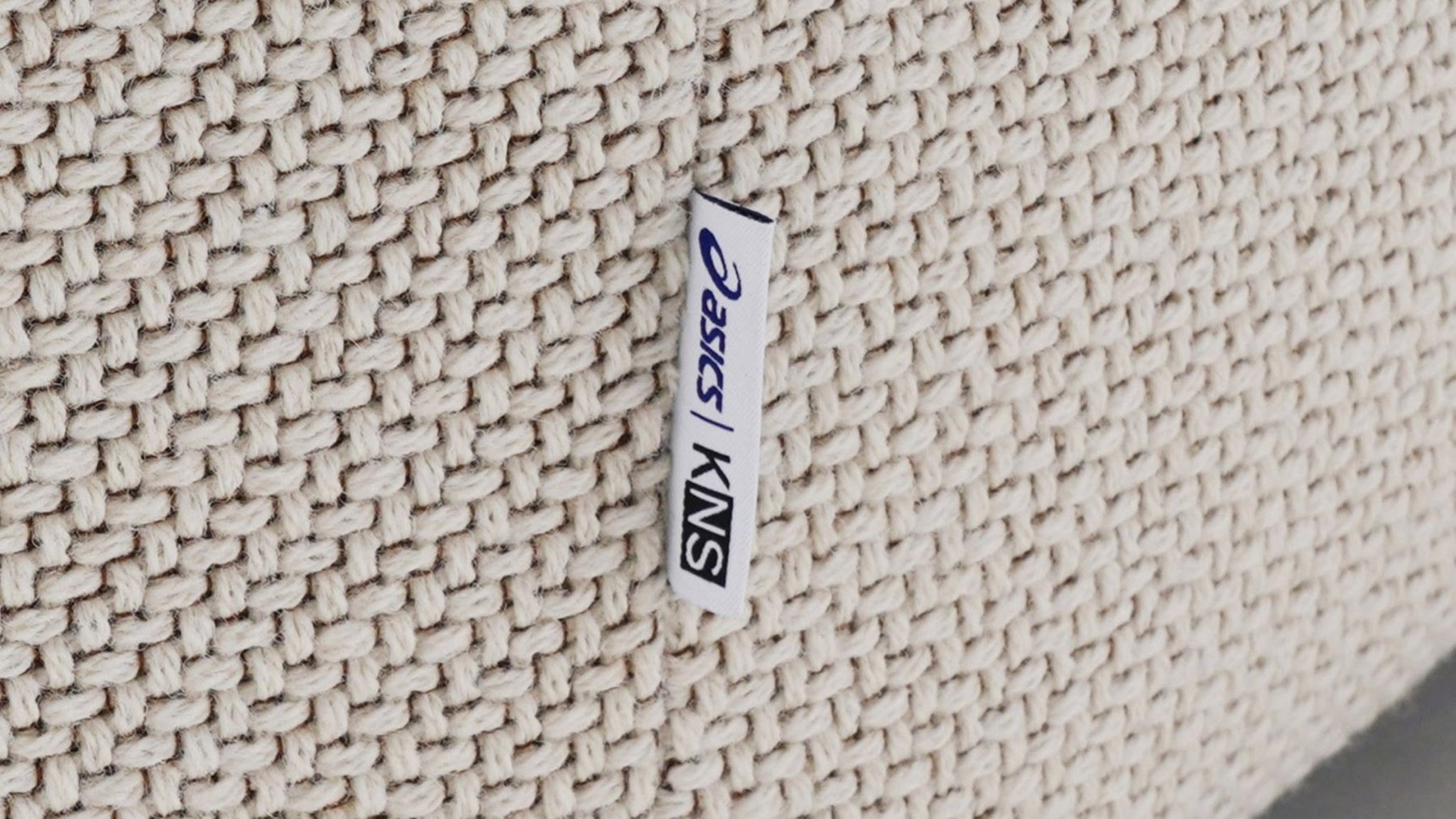 협업의 상징인 ASICS와 KNS 자수 태그가 달린 패브릭