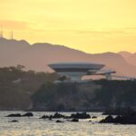 해 질 녘 해변 너머 MAC Niterói와 산 능선