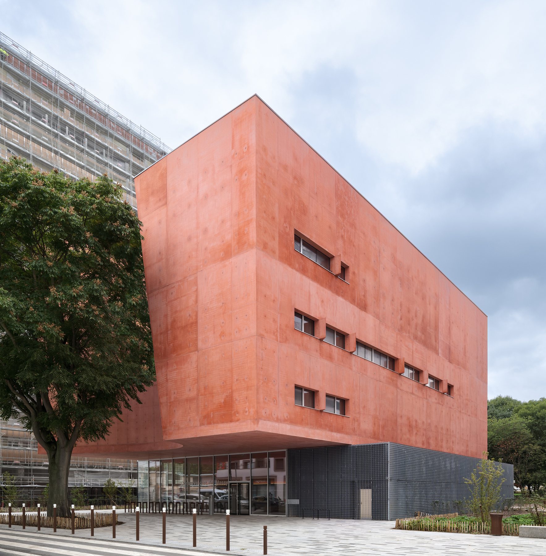 고층 아파트 사이에 선 테라코타 톤 오렌지 콘크리트 큐브 Massy Conservatoire 측면 외관