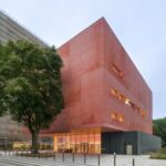해 질 녘 저층 유리벽에 불이 켜진 프랑스 예술학교 Massy Conservatoire 외관과 가죽나무