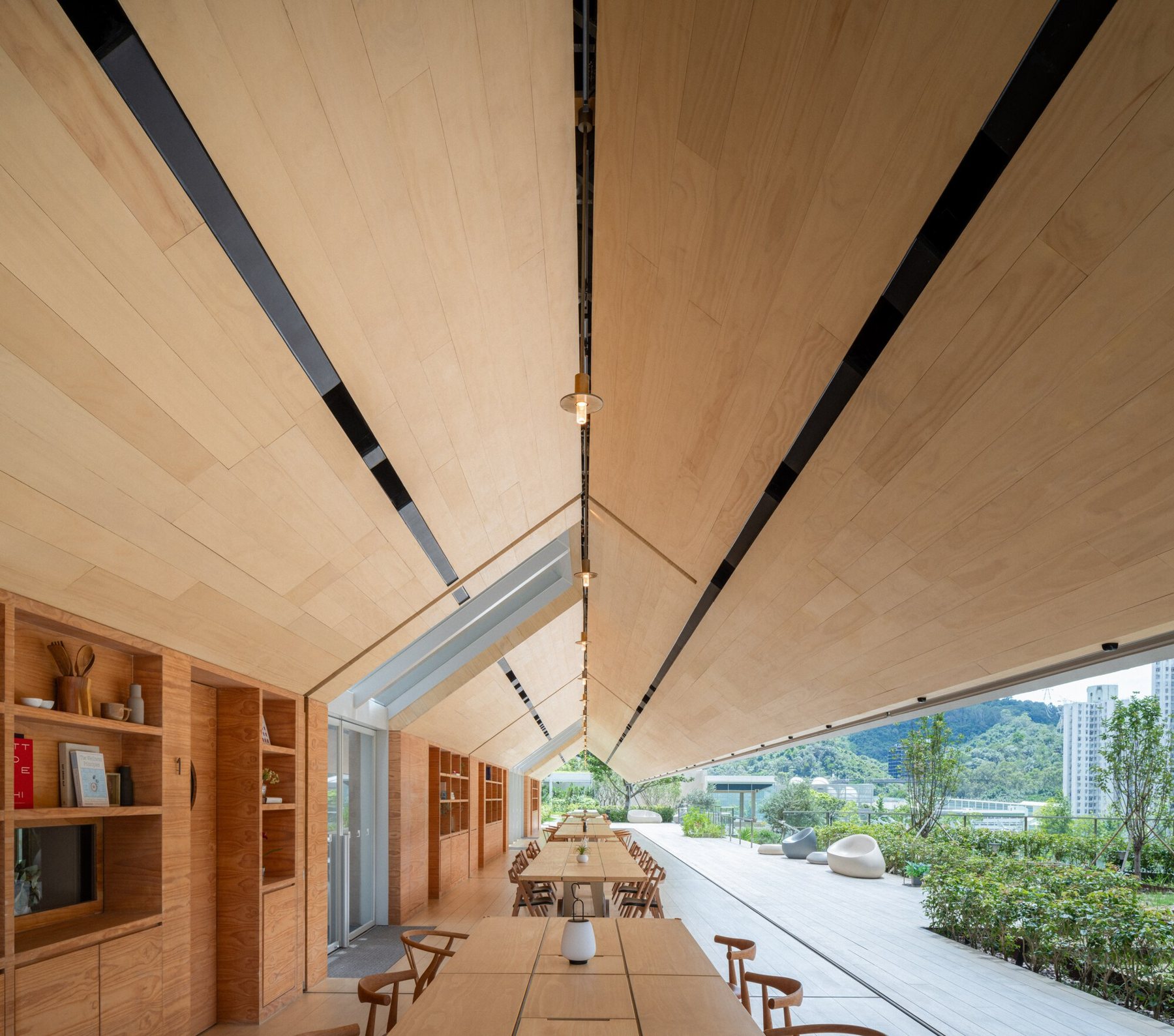 박공 천장 아래 레일 위 공용 식탁이 길게 놓인 Pavilia Farm Farm House 내부
