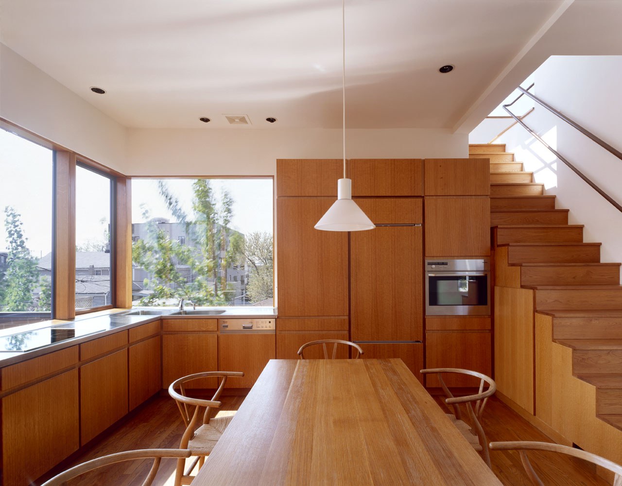 오크 수납장과 화이트 펜던트 조명이 있는 Pfanner House 주방
