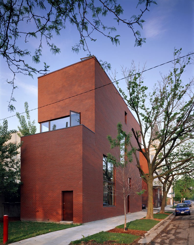 담장 없이 잔디와 나무를 둔 Pfanner House 측면 마당과 벽돌 외관