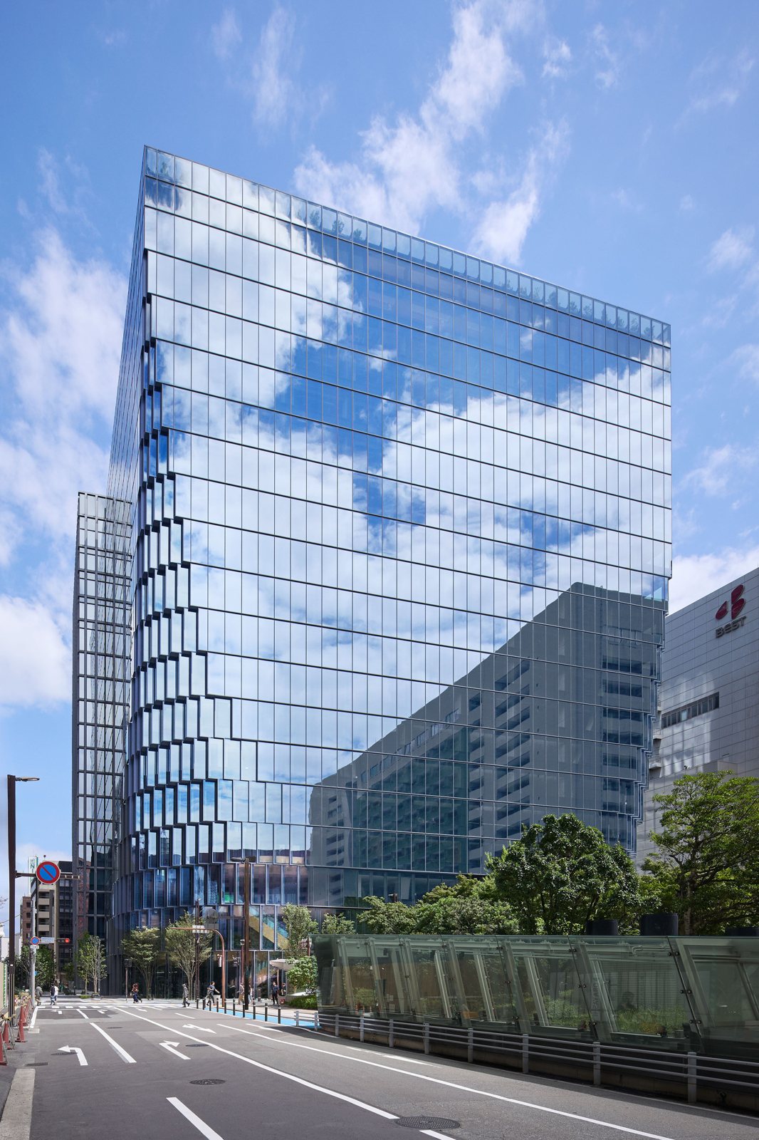 도로에서 올려다본 Tenjin Business Center II 유리 타워와 곡면 모서리