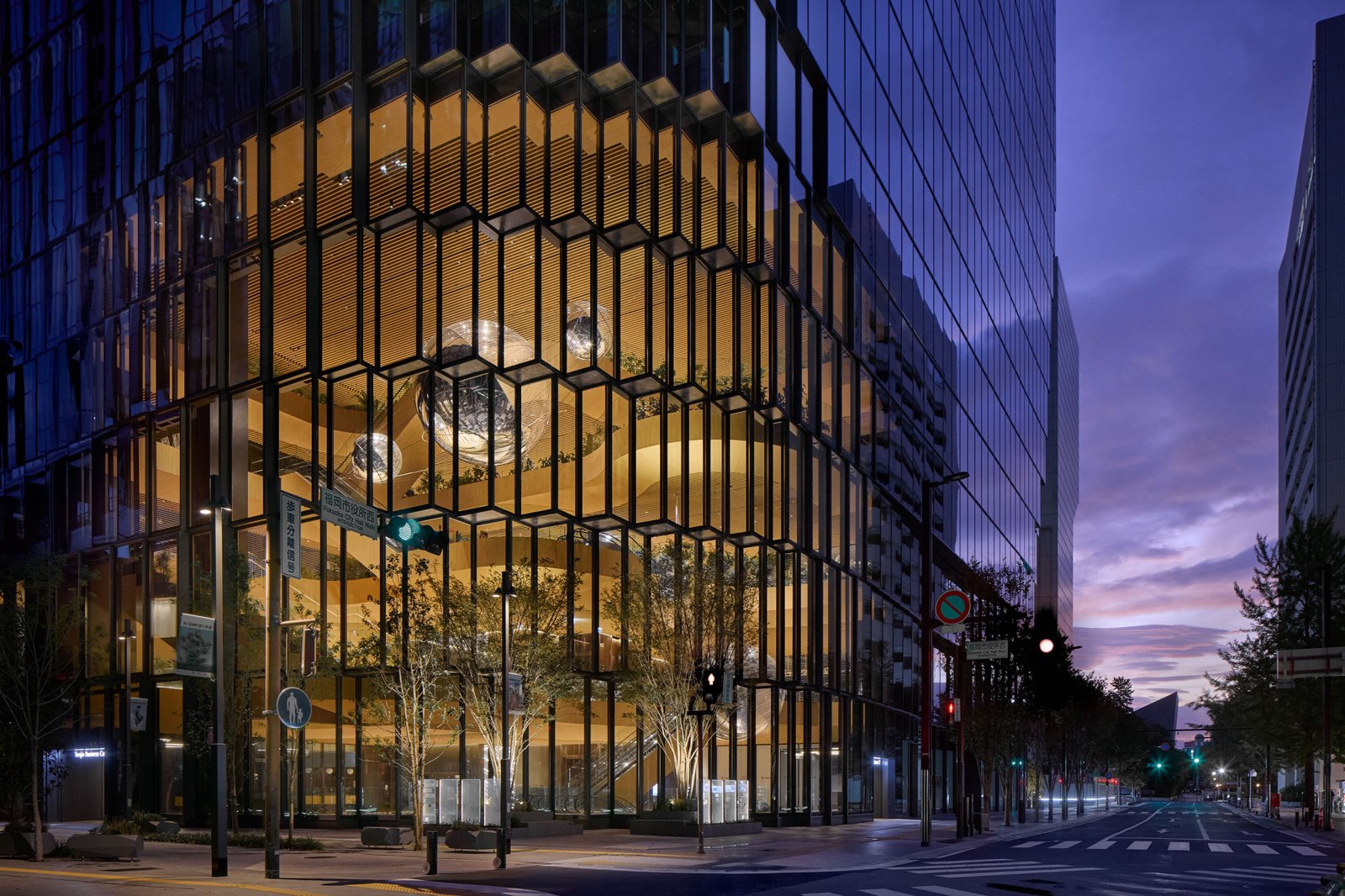 해 질 녘 목재 톤 아트리움이 환하게 드러난 Tenjin Business Center II 모서리 야경