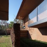 레드 톤 벽과 화산석, 블랙 메탈 창틀이 만난 Red Valley Dwellings 외벽 디테일
