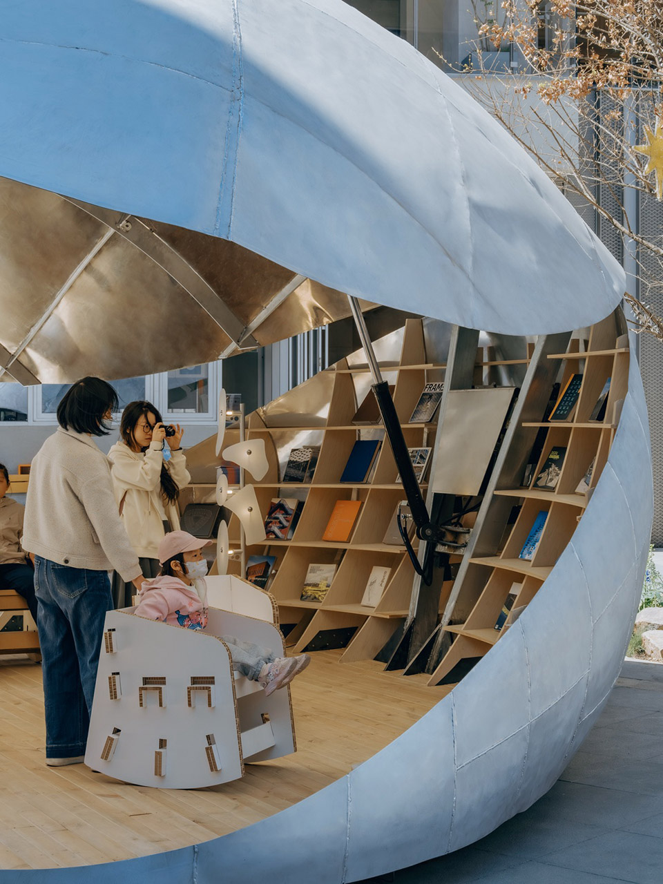 쉘 곡면을 따라 계단처럼 내려앉는 Shell Book Pavilion 부채꼴 목재 서가