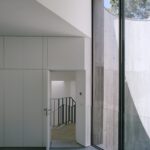 콘크리트 곡면 벽을 마주한 Trefoil House 방의 세로 통창