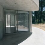 곡면 처마 아래 통유리가 들어간 Trefoil House 파티오 쪽 입면