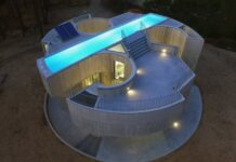 해 진 뒤 옥상 수영장에 불이 켜진 Trefoil House 콘크리트 주택 항공 전경