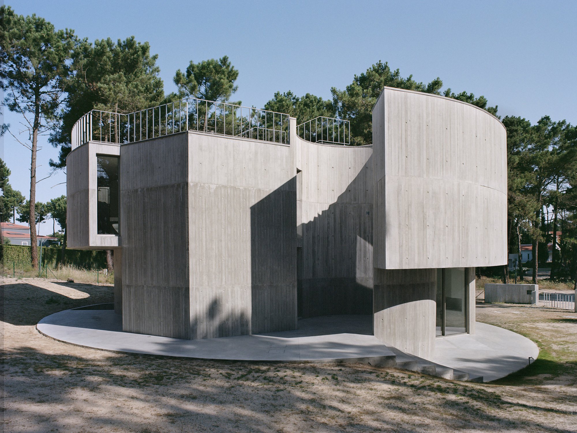 경사진 모래 대지 위에 불규칙하게 앉은 Trefoil House 외관