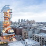 저녁 하늘 아래 Washington Heights 주거지 위로 솟은 Vagelos Education Center