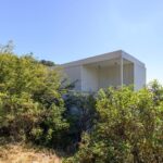 덤불 사이로 보이는 White Modular House의 화이트 외벽