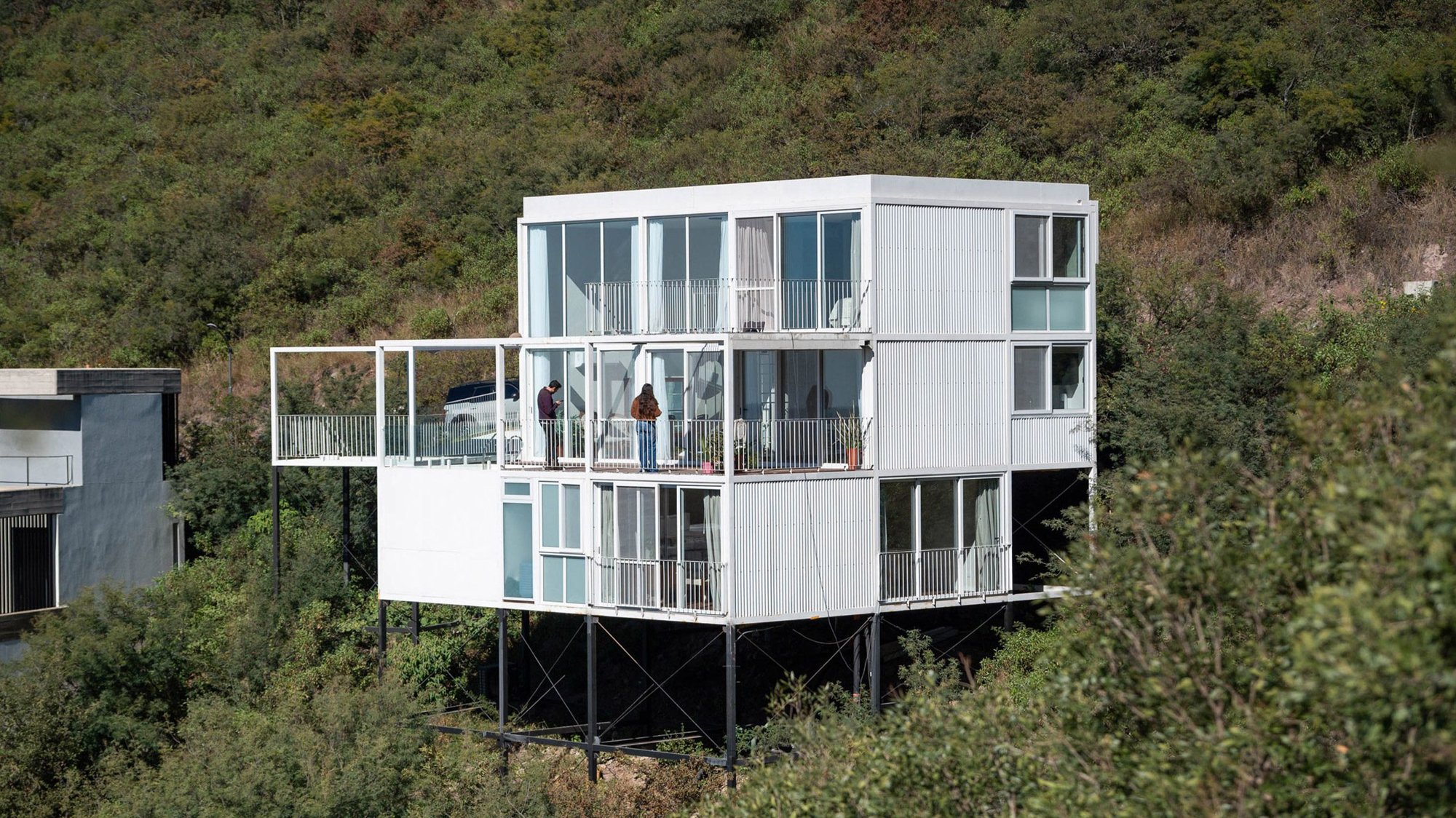 산비탈 숲 위에 철골 기둥으로 띄운 화이트 모듈러 주택 White Modular House 측면 외관
